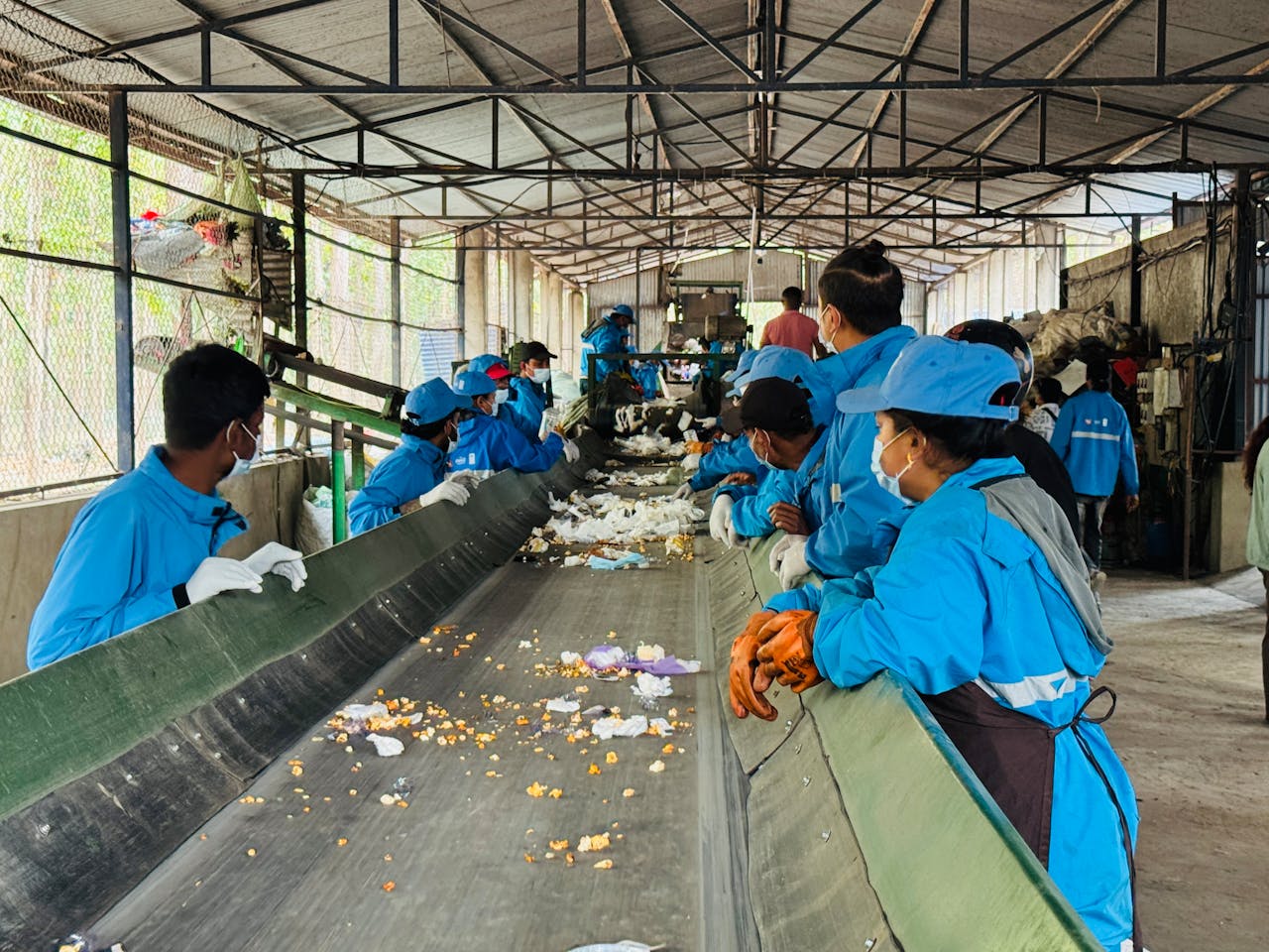Workers sorting recyclable materials at an indoor facility in Butwal, Nepal, promoting waste management.